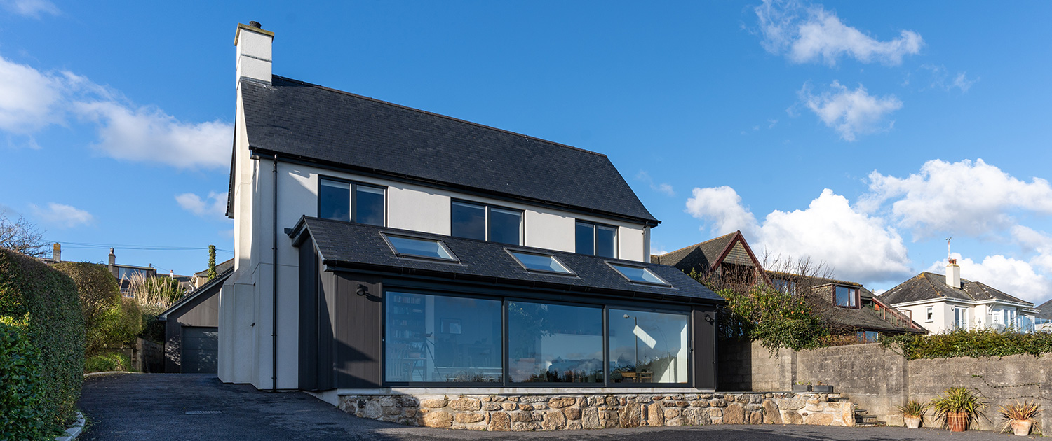 Our roofers in Penzance work: a detached house with a fabulous new roof in Penzance, with blue sky behind.